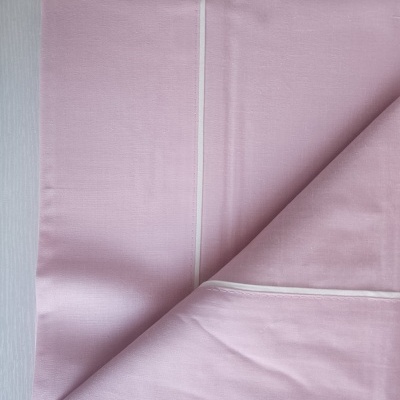 Lençol cor-de-rosa claro com costura branca dobrado sobre superfície clara