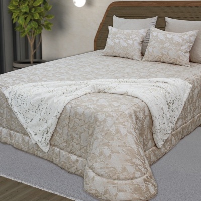 Cama com edredão bege com padrão floral e manta branca com detalhes dourados