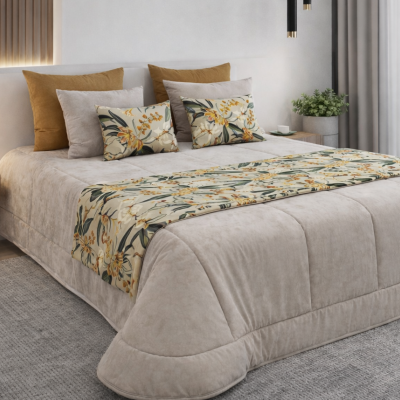 Cama de casal com edredão bege, almofadas castanhas e cinzentas, pano decorativo floral, tapete cinzento, candeeiro e plantas.