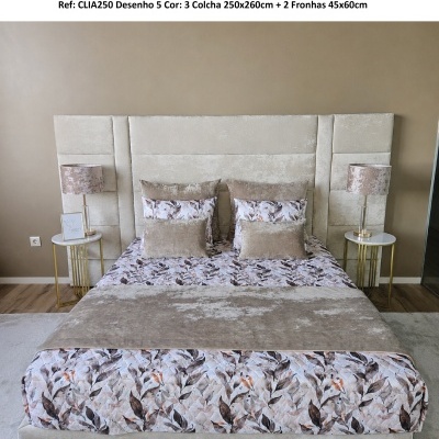 Colcha floral castanha e bege em cama com cabeceira estofada clara num quarto