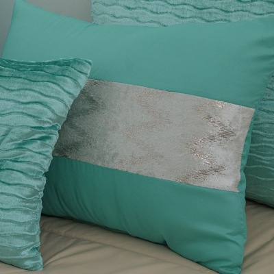 Três almofadas verdes decorativas, duas com textura ondulada e uma lisa com faixa prateada, em superfície bege