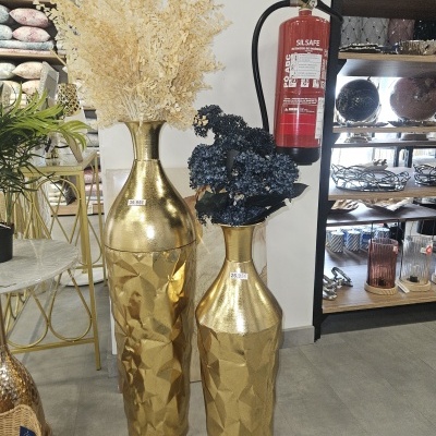 Duas jarras douradas decorativas com flores e extintor ao lado.