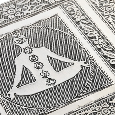 Placa decorativa metálica com figura humana e chakras em posição de lótus