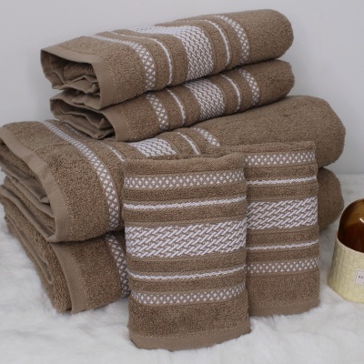 Conjunto de toalhas castanhas com riscas brancas e frasco decorativo com raminhos