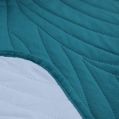 Tecidos matelassados azul turquesa e branco com padrão ondulado, sobrepostos.