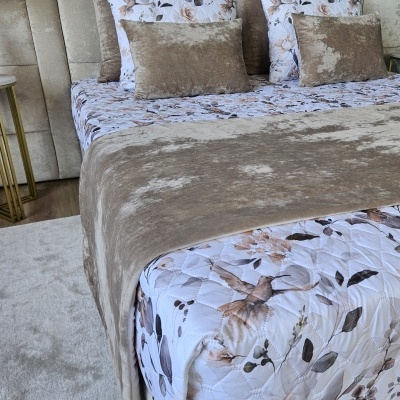 Cama com cabeceira estofada e lençol com padrão floral