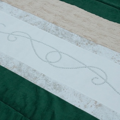 Tecido decorativo verde, bege e branco com padrão ornamental feito de pedrinhas