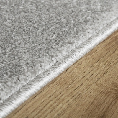 Tapete cinzento claro com borda branca sobre pavimento de madeira