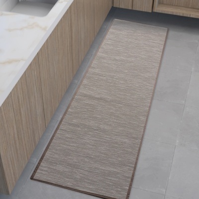 Tapete passadeira cinzento com borda castanha numa cozinha com armários de madeira clara e bancada branca