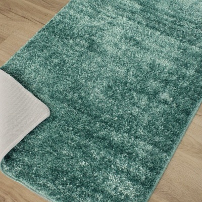 Tapete macio verde com pelo alto sobre chão de madeira clara