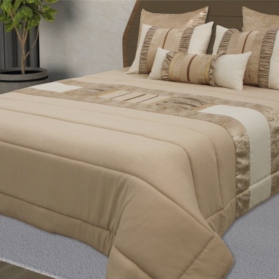 Cama com colcha bege e almofadas decorativas em bege e dourado sobre tapete cinza