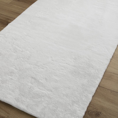 Tapete branco felpudo sobre chão de madeira