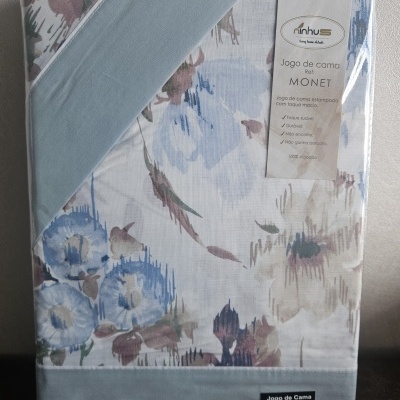 Jogo de cama com estampa floral azul e tecido azul liso em embalagem com etiqueta