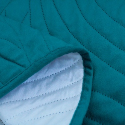 Tecido acolchoado verde-azulado com interior branco e costuras onduladas.