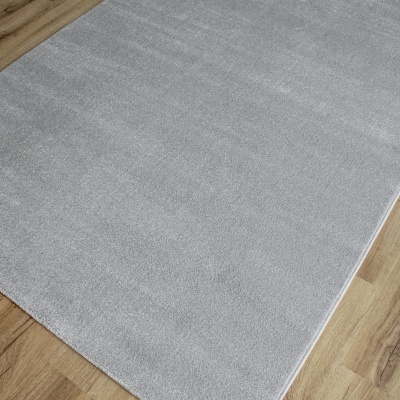 Tapete cinza claro sobre chão de madeira clara