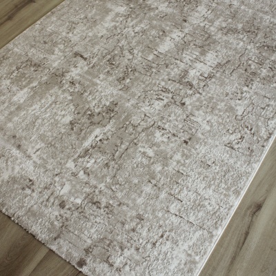 Tapete beige com padrões castanhos sobre chão de madeira