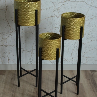 Três floreiras douradas decorativas em suportes metálicos pretos