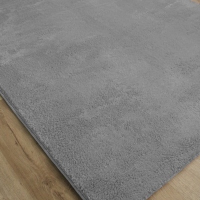 Tapete cinza claro macio sobre chão de madeira.