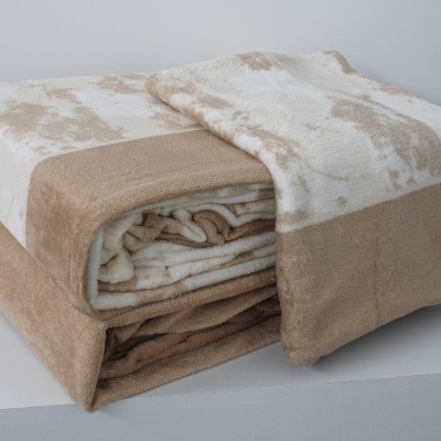 Manta de tecido macio bege e creme com padrão manchado dobrada