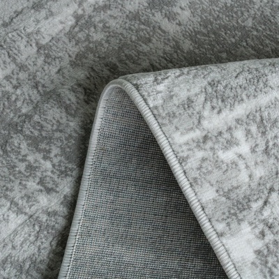 Tapete cinzento com padrão texturado e bordas costuradas.