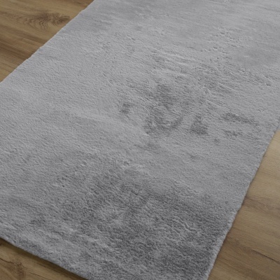 Tapete cinzento claro felpudo sobre chão de madeira