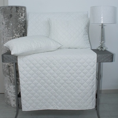 cobre sofá branco matelassê com almofadas em mesa cinzenta com abajur