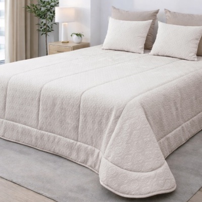 Colcha bege claro com padrão floral e almofadas decorativas numa cama em quarto minimalista