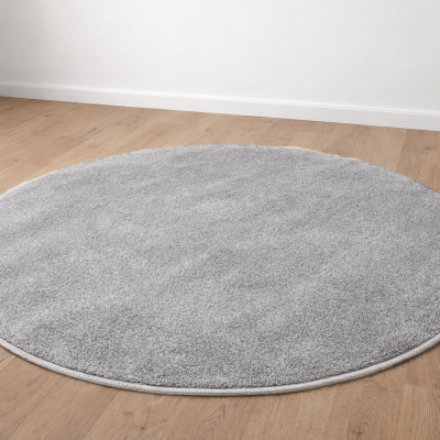 Tapete redondo cinza claro felpudo sobre chão de madeira clara