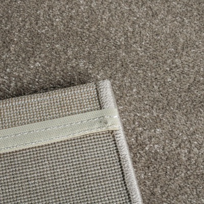 Tapete cinzento claro com verso tecido bege e branco, bordas costuradas.