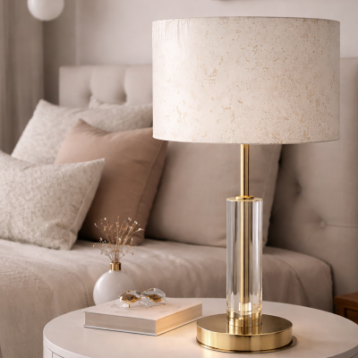 Abajur com base de metal dourado e cúpula creme sobre mesa redonda branca