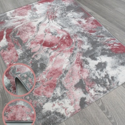 Tapete decorativo abstrato rosa e cinza sobre piso de madeira