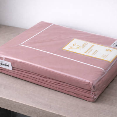 Lençol rosa embalado em plástico transparente com etiqueta Coilbry na mesa