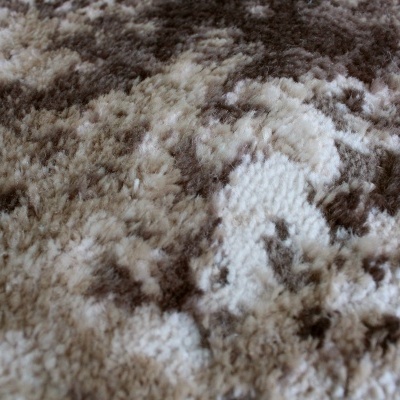 Tapete felpudo com padrão abstrato em tons de bege e castanho.
