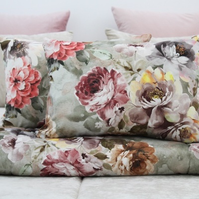Edredão e almofada com padrão floral colorido sobre cama com almofadas cor de rosa e bege