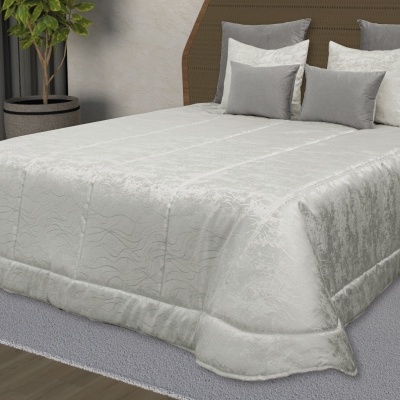 Cobertura de cama verde-claro com almofadas cinzas e cabeceira de madeira num quarto moderno