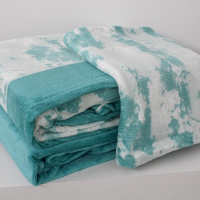 Manta dobrada azul turquesa e branca em superfície branca