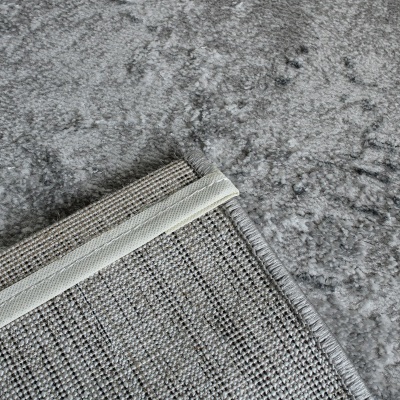 Tapete cinza claro com padrão abstrato e verso em tecido trançado