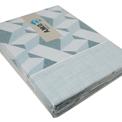 Colcha dobrada com padrão geométrico azul e branco embalada em plástico