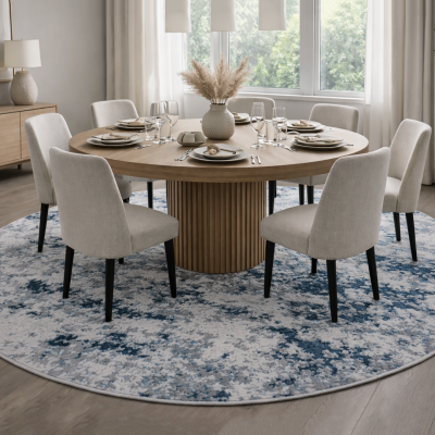 Mesa de jantar redonda de madeira clara com cadeiras estofadas bege claro e tapete redondo azul e branco