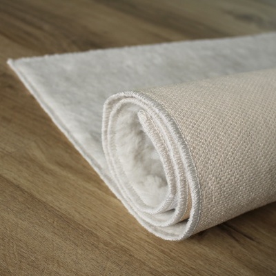 Tapete branco enrolado sobre chão de madeira