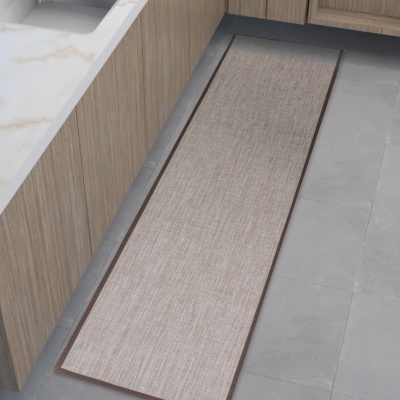 Tapete comprido bege claro com acabamento castanho no chão de cozinha com balcão de madeira clara e pia de inox.