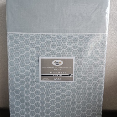 Jogo de cama cinza estampado com padrão hexagonal e etiqueta da marca Minhus