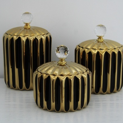 Três frascos decorativos dourados e pretos com tampas e puxadores em cristal