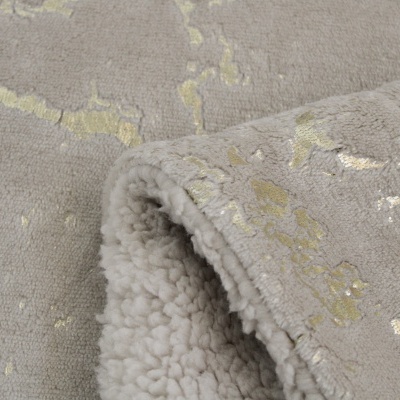 Detalhe de tecido felpudo cinza com padrão dourado metálico e interior aveludado branco dobrado