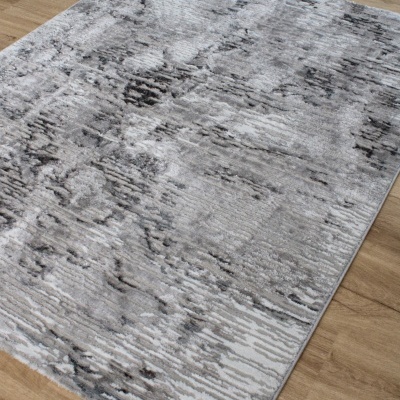 Tapete cinza com padrão abstrato colocado em chão de madeira clara