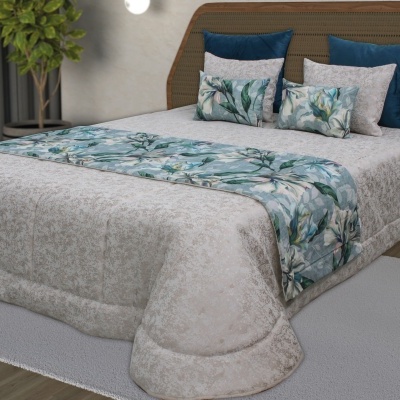 Cama com edredão bege e almofadas decorativas florais azuis.