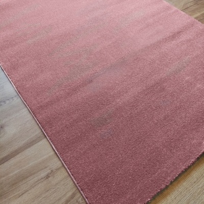 Tapete rosa retangular tecido felpudo sobre chão de madeira clara