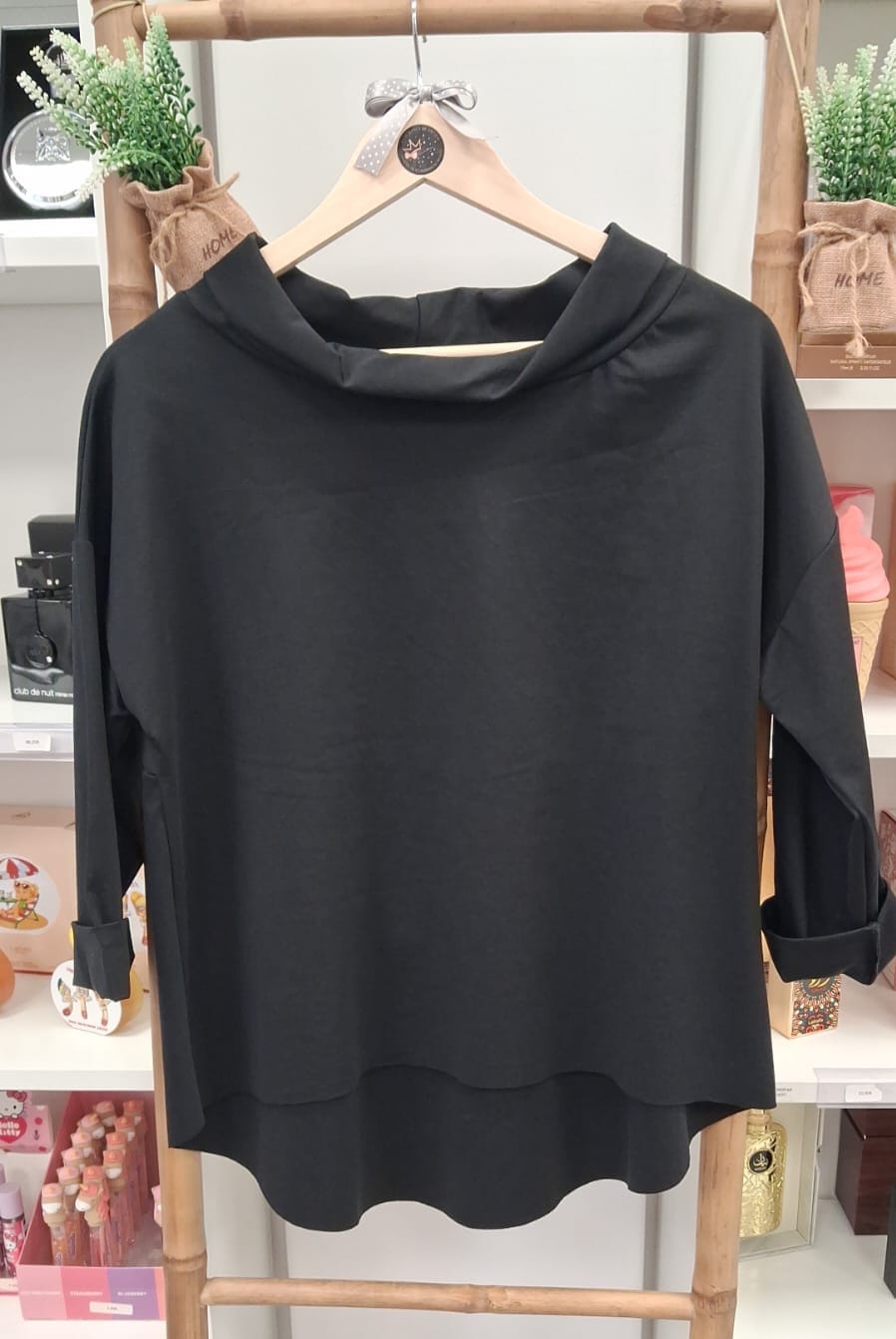 Camisola preta de mangas compridas com gola alta pendurada num cabide de madeira