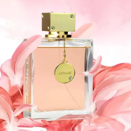 Frasco de perfume ARMAF com líquido rosa e tampa dourada envolto em flores cor-de-rosa