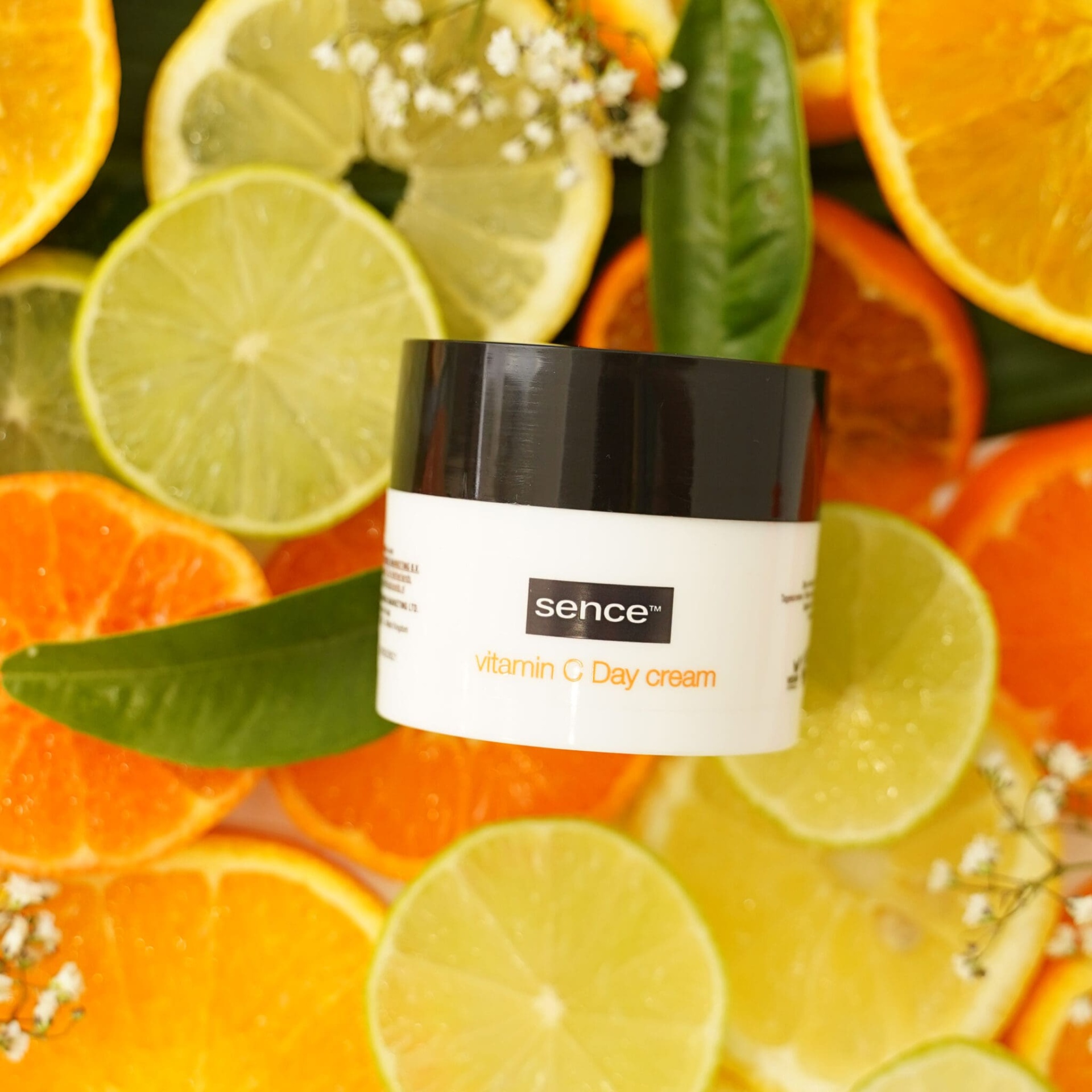Frasco de vitamina C Day cream da sence sobre fatias de frutas cítricas e folhas verdes